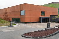 Auf zum Museum  Nachdem wir wieder um 7:00 Uhr aufgestanden sind, zeigt ein Blick nach draußen überwiegend blauen Himmel – allerdings stürmt es immer noch heftig. Aber zuerst geht es zum inbegriffenen Frühstück im Hotelrestaurant. Das Buffet ist weitläufig, freie Tische gibt es reichlich und die Toaster sind beim Toasten ebenso meditativ wie die gestrige Kaffeemaschine. Dafür ist der knusprige Speck kalt und die Würstchen sind alle, aber sonst kann man nicht meckern.  Da der Sturm inzwischen Orkanstärke erreicht und laut Internet die gefühlte Temperatur bei 0° – minus 2°C liegen soll, packen wir uns erst mal warm ein und machen uns dann auf den Weg zum geplanten Eldheimar Museumsbesuch (eine gute Empfehlung übrigens für regnerische und windige Tage – also fast für immer!).  Als wir eine Minute später vor dem Museum ankommen, freuen wir uns, nicht auf Menschenmassen zu stoßen – was sich dann spontan dadurch erklärt, dass das Museum nicht wie im Reiseführer behauptet um 10:00 Uhr, sondern erst um 11:00 Uhr öffnet.