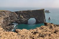 Dyrhólaey útsýnisstaður  Auf der östlichen Seite der leuchtturmgekrönten Klippenspitze befindet sich der "Dyrhólaey útsýnisstaður", der Aussichtspunkt Dyrhólaey, von dem man einen tollen Blick auf einen von zwei Durchbrüchen gekennzeichneten Brückenkopf hat. Rundherum sieht man im Dunst weitere kleine Felseninseln, viele von ihnen ebenfalls mit wasserumspülten Durchbrüchen.