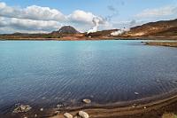 Azurblau  Während Maren im Auto auf mich wartet, blättert sie im Reiseführer und liest, dass man auch noch Richtung Kraflavulkan weiterfahren kann. Dort soll es eine sehr lohnenswerte Strecke zum Leirhnjúkur geben, einem Lehmberg, um den herum es einen Pfad zu weiteren Fumarolen geben soll.  Warum nicht? Wir fahren auf dem gleichen Weg zurück und passieren jetzt zum dritten Mal einen auffällig blauen See, an dessen gegenüberliegendem Ufer Islands ältestes Geothermalkraftwerk weiße Dampfwolken ausstößt. Früher war der Überlauf des Kraftwerks ein beliebter Badesee, mittlerweile ist er dafür aber zu heiß.