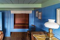 Bláa stofa  Das rechtsseitige Gästezimmer mit dem zusätzlichen Eingang an der Hausfront wurde 1841 eingerichtet. Ein paar Zeilen eines berühmten Gedichtes sind in den Vorhang des Bettes eingestickt und erinnern an den geschätzten isländischen Dichter Jónas Hallgrimson aus Tröllaskagi, der neben anderen prominenten Gästen hier genächtigt hat. Der heute sehr wohnlich wirkende Raum ähnelte ursprünglich wohl eher den Betriebsräumen, die auch heute noch mit Feldsteinen verkleidete Wände besitzen.  Der 20 m lange Zentralgang führt durch einen geschlossenen Komplex im Fischgrätmuster aufgeschichteter Torfsoden, der die von meterdicken Schichten getrennten 'Einzelhäuser' umschließt. Diese Bauweise isolierte unter den isländischen Bedingungen so gut, dass das Gehöft ohne zusätzliche Heizung auskam und nur von der Körperwärme seiner Bewohner erwärmt wurde.
