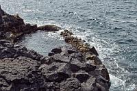 Brimketetill  Das Gleiche gilt auch für das noch größere Becken auf der linken Seite der Plattform, dem offensichtlich der mit "Brandungskessel" ins Deutsche übersetzte Name gilt. Tollkühne Badefreunde sehen sich neben dem anspruchsvollen Abstieg zudem mit heftigen Brandungswellen konfrontiert, die einen durch die Felslücke ins Meer zu reißen vermögen.  Bereits zu Hause hatten wir spekuliert, was uns in Grindavík erwarten würde, wo es erst 2023 zu heftigen Ausbrüchen riesiger Lavamengen aus dem schon seit langem bekannten Erdriss gekommen war. Wochenlang gab es in den weltweit verbreiteten Nachrichten Spekulationen darüber, ob Grindavík womöglich evakuiert werden müßte. Glücklicherweise kamen die Ausbrüche zum Erliegen, bevor es zu größeren Schäden kam. Wir sind gespannt, welche Zeugnisse der Ereignisse es in Grindavík noch zu sehen gibt. Auffällig häufen sich entlang des Weges nach Grindavík jedenfalls unübersehbar weiße Dampfsäulen, die in einiger Entfernung aus der mit dunkler Lava bedeckten Landschaft aufsteigen.