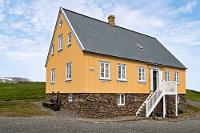 Caféhaus  Heute verlaufen sich trotz des fortgeschrittenen Vormittags erfreulicherweise nur wenige Besucher auf dem großen Gelände. Hier macht es sich noch bemerkbar, dass wir in der Vorsaison reisen und die meisten Touristen sich als Passagiere der großen Kreuzfahrtdampfer hauptsächlich im Süden der Insel ballen. Zwischen dem am Eingang gelegenen, noch ziemlich leeren Parkplatz und der Hauptattraktion, den Torfhäusern, führt ein Kiesweg an zwei schön gepflegten Häusern des 19. Jahrhunderts vorbei – eines von ihnen, das graue, diente dem örtlichen Pfarrer als Wohnsitz, ist begehbar und zeigt mit Originalkleidung ausgestattete und auf 'antik' getrimmte Schaufensterpuppen hinter Glaswänden. Das zweite, hellorangefarbene Haus hingegen, war früher eine Mädchenschule und beherbergt heute das "Áskaffi".