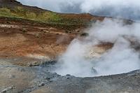 Fyrsta heita laugin  (der erste der heißen Pools :-) In der Hoffnung, dass sich das Wetter nicht unangenehmer bemerkbar macht, hält uns jetzt nichts, das eigentliche Ziel des Abstechers von der Küstenstraße zu erkunden: das Thermalgebiet Seltún. Der großzügige Parkplatz direkt an der Straße 42 ist nur zu ca. einem Drittel gefüllt und an dem nebenstehenden Rangerhäuschen mit öffentlicher Toilette wird nicht einmal ein Eintritt oder Parkgebühr verlangt! Ein Zustand, der leider in Island kein Standard ist, denn fast überall, wo es etwas zu sehen gibt, wird sowohl ein Eintrittsobolus fällig, sowie eine Parkgebühr, die entweder an entsprechenden Automaten oder über eine nicht ganz einfach zu durchschauende App direkt vom Konto zu begleichen ist.