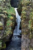 Gljúfrafoss  Der 'verborgene Wasserfall', den wir schließlich erreichen, ist in der Tat erst zu entdecken, wenn man direkt davor steht. Einige mit Gummistiefeln ausgestattete Wagemutige haben sich, vorsichtig über die rutschigen Steine am Schluchtrand balancierend, bis auf den großen Felsen unterhalb des Falls vorgearbeitet. Dies kann uns heute nicht mehr locken – wir sind so schon nass genug. Ich knipse schon munter mit der Spiegelreflex drauflos, als Maren erschrocken realisiert, dass der unersetzliche SONY Camcorder nicht mehr funktioniert! F*ck!