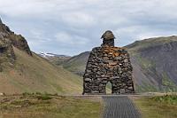 Grobschlächtig  Wir gehen im Bogen zum Parkplatz zurück, vorbei an dem unübersehbaren Denkmal, welches wir Ignoranten nur von hinten fotografiert haben. Wobei... von vorne sieht es auch nicht anders aus, nur, dass noch ein Denkmalstein davorsteht. Dieser Steinklotz stellt nicht etwa nur einen Steinklotz dar, sondern den Berserker Bárður Snæfellsás, einen der ersten Siedler in dieser Gegend und deshalb so klobig und groß, weil er der Sage nach von Trollen und Riesen (oder vom Eismeerkönig Dumbr – so genau weiß man das nicht) abstammte. Als typischer Berserker neigte er zu Berserkertaten und wurde nicht zuletzt wegen der Auseinandersetzung mit seinem Bruder bekannt, dessen Sohn Rauðfeldur er in die Rauðfeldsgjá Schlucht warf. Er soll nach diesen Ereignissen im Snæfellsjökull, dem Gletscher des größten Berges der Halbinsel verschwunden sein und noch heute als Schutzgeist von den Bewohnern Snæfellsnes' angerufen werden.