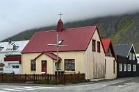 Kaþólka Kirkjan  Unser Zimmer liegt im ersten Stock, leicht über die Treppe zu erreichen. Für das Gepäck bietet sich aber der Fahrstuhl an – eine einfache Plattform mit Bedienpanel, umgeben von roh verputzten Schachtwänden. Maren kriegt den Horror: "Damit fahre ICH nicht!", steigt aus und stapft die Treppe hoch. Ich meistere die Technik hingegen souverän und drücke den Liftknopf solange, bis der erste Stock erreicht ist ;-).  Maren bricht noch einmal auf, um ein empfohlenes Souvenirgeschäft aufzusuchen, welches sich aber als Kunsthandwerksladen entpuppt, mit ebenfalls künstlerischen Preisen. Statt dessen bringt sie vom Stadtausflug lieber das Foto einer winzig kleinen katholischen Kirche mit zurück, einer echten Rarität im protestantischen Island, sowie das Bild eines verlebten Kahns, der sehnsüchtig auf den Fjord blickt.