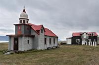 Listasafn Samúel Jónsson  Da wir nicht baden wollen, fahren wir weiter auf der einsamen Küstenstraße. Nicht ein Auto begegnet uns und auch, als wir in Selárdalur ankommen, zeigt sich auf dem weit in die Bergwelt hineinreichenden, flachen Sandland keinerlei Leben.  Unübersehbar stehen aber, etwas zurückgesetzt vom Ufer, ein Kirchlein und zwei hausähnliche Gebäude rechtsseitig der hier endenden Straße. Außer unserem ist auch kein anderes Fahrzeug zu sehen, als wir auf dem kleinen Parkplatz anhalten. Wir sind aber kaum ausgestiegen und am offenen Tor zu diesem Ensemble angelangt, als eine sehr resolute Dame aus dem hinteren Wohnhaus auf uns zustrebt.