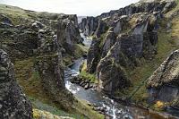 Malerisch  Nach dem Frühstück erkundigt sich Maren beim netten Rezeptionisten, ob man den Parkplatz bei der Fjaðrárgljúfur Schlucht wirklich nur mit der Parka-App bezahlen kann, was dieser bejaht und gleichzeitig versichert, dass dies trotz der zu hinterlegenden Kreditkarte völlig problemlos und sicher sei, da die App ja schließlich von der isländischen Regierung sei. Nun ja... Die App wird also installiert, wider Erwarten brauchen wir sie an dem gut gefüllten Zielparkplatz heute dann doch nicht, da man auch direkt mit der Kreditkarte am Automaten zahlen kann.  Schon der Anblick der sich öffnenden Schlucht verspricht einige lohnende Fotomotive und nachdem wir auf der rechten Flussseite einen steilen Pfad erklommen haben, geht es – entlang bizarrer Felsen, denen man auf verschiedenen Aussichtsplattformen nahe kommt – auf etwa 1,5 km Länge bis zum Ende des Canyons.