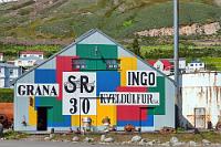 Mut zur Farbe  Weiter geht es durch den Héðinsfjarðargöng, in Wirklichkeit zwei, nur durch einen kurzen Tageslichtabschnitt getrennte, 6 und 4 km lange Tunnel, an deren Ende der Siglufjörður ("Schiffsmastfjord") liegt, mit dem gleichnamigen Fischerdorf am westlichen Fjordufer. Malerisch ist es hier, auf der einen Seite hochaufragende Berge, deren Flanken unterhalb der aktuellen Schneegrenze mit Lawinenschutzzäunen bestückt sind, während rechts der Straße der blaue Fjord glitzert. Die Durchgangsstraße entlang des Hafens weist einige interessante, teilweise bunt bemalte Gebäude auf, die alle etwas mit der örtlichen Heringswirtschaft zu tun haben.