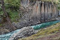 Steinkunst  Bereits vom hochgelegenen Weg haben wir fast ständig einen Blick hinab in die Schlucht, durch die ein grünschimmerndes Flüßchen fließt. Nach ca. 2 km Fußmarsch (die eine sagt einfach zu gehen, der andere sagt eher hochalpine Herausforderung :-) senkt sich der Weg und vis-à-vis stehen wir der ersten skurril gefalteten Basaltkolumne gegenüber. Wie von uns kalkuliert, stellt sich die Ostseite als genau richtig heraus; die Aussichtsplattformen befinden sich zwar auf dem gegenüber liegenden Flußufer, die beeindruckendere Aussicht hat man aber von dieser Seite.
