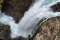 Strompgljúfrafoss  Es scheint, als hätten die Reisebusse ein Signal bekommen. Als wir wieder für die letzten Meter ins Auto gestiegen sind, kommen uns etliche abfahrende Busse entgegen. Wahrscheinlich wartet irgendwo (Þingeyri?) ein Kreuzfahrer auf sie, denn als wir auf dem Parkplatz eintreffen, stehen nur noch drei Busse in ihrer Parkspur. Nervig ist, dass der Parkplatz – entgegen den Aussagen des Reiseführers – inzwischen gebührenpflichtig geworden ist. Könnte man die Gebühr über die App bezahlen, wäre dies ja nicht schlimm. Hier aber muß ein QR-Code abgescannt werden, was uns etwas ratlos läßt, gehören wir doch zum kleinen Teil der Offline-Menschheit. Nun, wir verschieben die Lösung des Problems und machen uns daran, die steilen Stufen entlang des Falles zu ersteigen.
