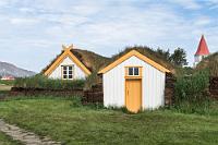 Suðudyr  Die hintere Südansicht zeigt links das Fenster der Bauernfamilie und in der Mitte die "Südtür", der Ein- und Ausgang, durch den frisches Wasser und Vorräte hinein, sowie Asche und Abfälle nach draußen gelangten. Außerdem diente die Tür als Notausgang, sollte im vorderen Gebäudeteil ein Feuer ausbrechen.   Hinter den mit dicken Torfschichten getrennten und nach außen isolierten 'Häusern' überragt der Kirchturm das Gehöft – natürlich nicht mehr der von Snorri Þorfinnsson erbaute, sondern der des 'Neubaus' aus dem 19. Jahrhundert. Auch die Fenster des Gehöftes dürften aktuellen Bedürfnissen angepaßt worden sein, denn in vergangenen Zeiten wurden lediglich die repräsentativen Räume wie die Gästezimmer mit wertvollem Glas ausgestattet, sämtliche anderen Räumlichkeiten erhielten ihr Licht mittels durchscheinender Kalbshäute.