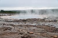 Unruheherd  Unübersehbar ist das zentrale steinerne Feld, welches den milchweißen Tümpel des "Strokkur Geyser" umgibt. Die derzeit noch relativ wenigen Besucher haben sich entlang der Kordelabsperrung an der Nordwestseite des Areals versammelt und warten offensichtlich gespannt auf den nächsten Ausbruch. Bei wechselnden Winden soll es ziemlich abenteuerlich sein, zuverlässig auszuschließen, von der nächsten Fontäne geduscht zu werden. Heute ist es aber nahezu windstill, so dass die leicht erhöhte Position die besten Sichtvoraussetzungen bietet.