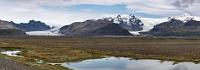 Vatnajökull  Von dem Rastplatz, den wir soeben verlassen haben, ist das mächtige Plateau des Vatnajökull bereits am Horizont zu sehen. Nur wenig später erreichen wir auf dem 'Hringvegur' die Gletscherfront, die sich bei bester Sicht mit dem Skaftafellsjökull und dem Svínafellsjökull präsentiert. Ein guter Grund, hier auf einen abzweigenden Feldweg einzubiegen, um diese Ansicht in einem Panorama festzuhalten.  Erstaunlicherweise hat auch erstmals seit unserer Ankunft der stürmische Wind nachgelassen und weil es noch früh am Nachmittag ist, beschließen wir, noch vor dem Einchecken im Hotel einen ersten Spaziergang zum Gletscherfuß des Svínafellsjökull zu machen.