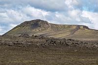 Wermutstropfen  Das einzig Interessante an diesem Bild ist der Zufahrtsweg, der sich an dem Hang des Ljótipollur hochschiebt und auf den wir gleich abbiegen werden, um einen Blick auf den Kratersee des Vulkans zu werfen.  Ein bißchen wehmütig ist uns schon zumute, dass wir schon morgen abend wieder in Hamburg sein werden, umgeben von dem typisch deutschen Wahnsinn, der uns langsam aber sicher in die nächste Katastrophe treibt und von dessen Auswüchsen wir hier am äußersten Rand Europas vier entspannte Wochen lang verschont geblieben sind. Und es sind nicht nur die Naturschönheiten, die uns für dieses Land eingenommen haben, sondern ganz besonders auch die Freundlichkeit und Entspanntheit der weit verstreut lebenden Isländer, denen man nur wünschen kann, dass ihre Zugehörigkeit zu Europa ausschließlich auf die Geologie beschränkt bleibt.