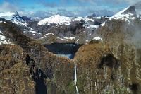 Leider nicht ganz drauf...  ...aber trotzdem immer noch ziemlich beeindruckend ist der Sutherland Falls, Neuseelands höchster Wasserfall, der in drei Stufen über insgesamt 580 m in die Tiefe fällt. Er entspringt direkt Lake Quill, einem Alpensee, der wiederum durch Wasserfälle gespeist wird, die von den umliegenden Gletschern produziert werden.  Eine Cessna ist kein Helikopter und kann deswegen nicht so dicht an den Fall manövriert werden, dass ein völlig kontrolliertes Foto möglich gewesen wäre. Bedingt durch die geringe Flughöhe aufgrund der Wettersituation mit tiefhängenden Wolken, waren wir froh, trotz des gekurvten Vorbeiflugs wenigstens noch diesen Anblick genießen zu können. : southern alps, südalpen, queenstown, fiordland, milford sound, sutherland falls